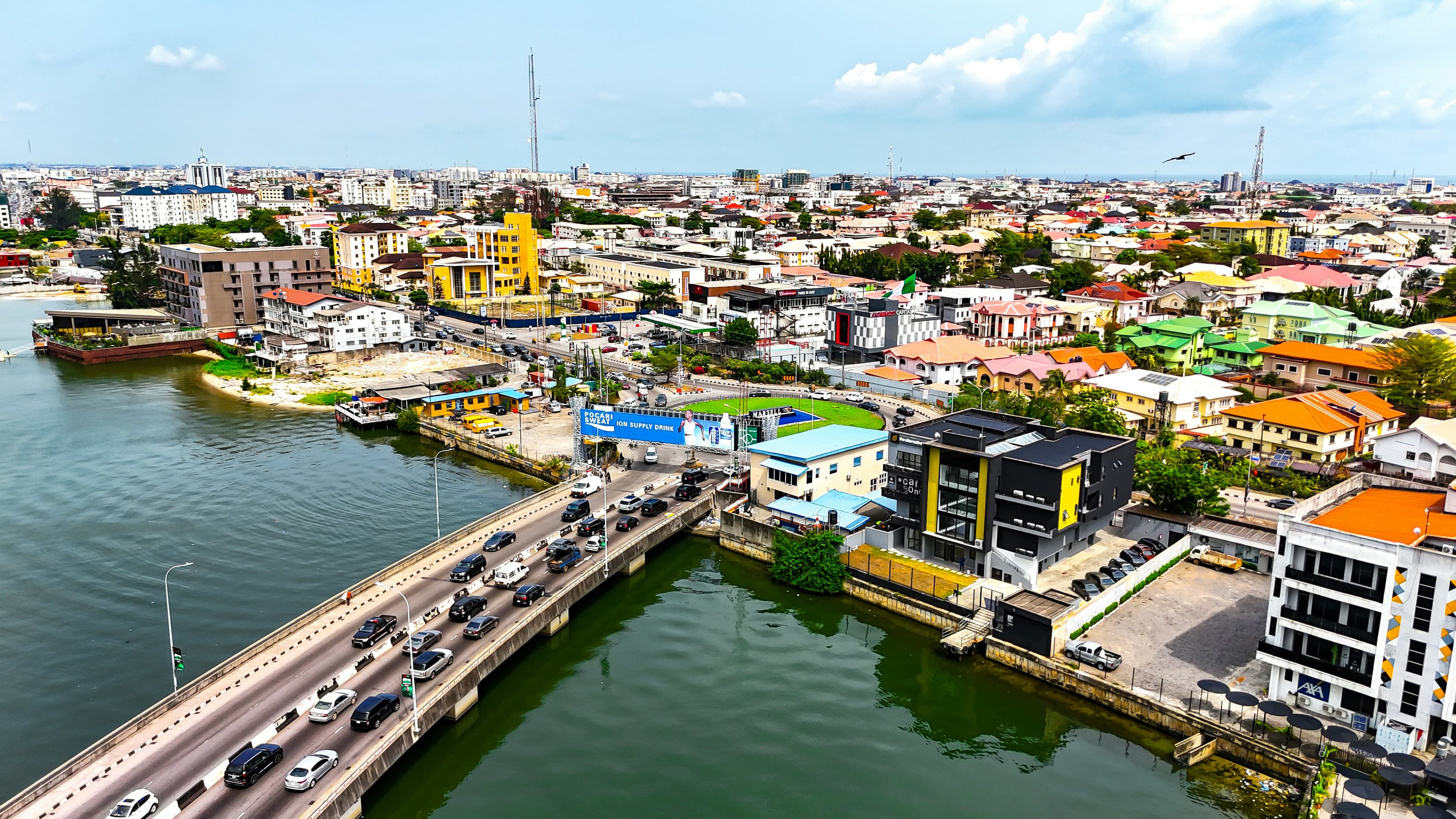 An aerial view of a dense, colourful Lagos skyline with mixed residential and commercial buildings